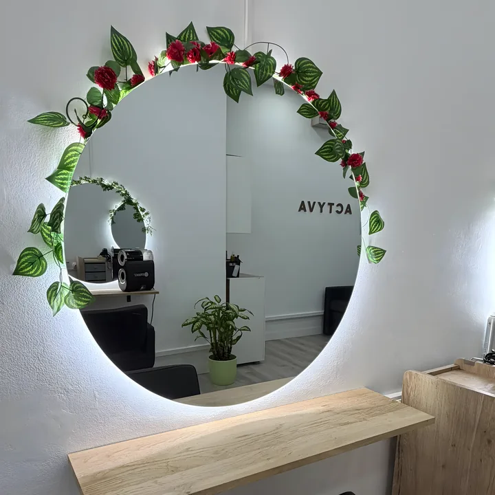 Tocador del sal&oacute;n con espejo redondo iluminado y guirnalda de hojas y rosas
