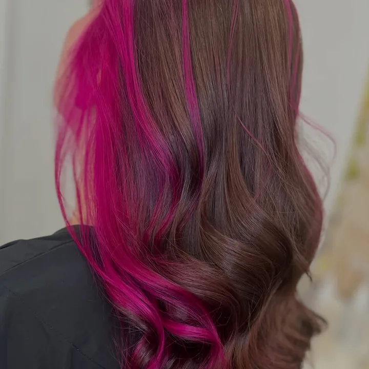 Melena casta&ntilde;a en ondas con una mecha magenta, vista de espaldas
