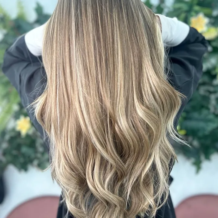 Melena larga con balayage, de espaldas, ante la pared de hiedra del sal&oacute;n